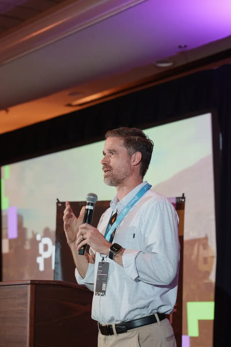 Adam Weeks speaking on stage at PressConf